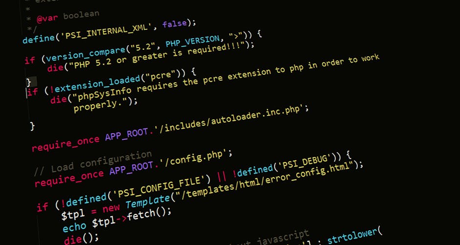 Photograph of a computer screen displaying lines of colorful programming code in various shades of red, green, blue, yellow, and white on a dark background. The code includes functions, variables, and